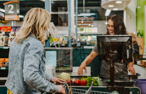 Woman checking out groceries and talking with woman cashier